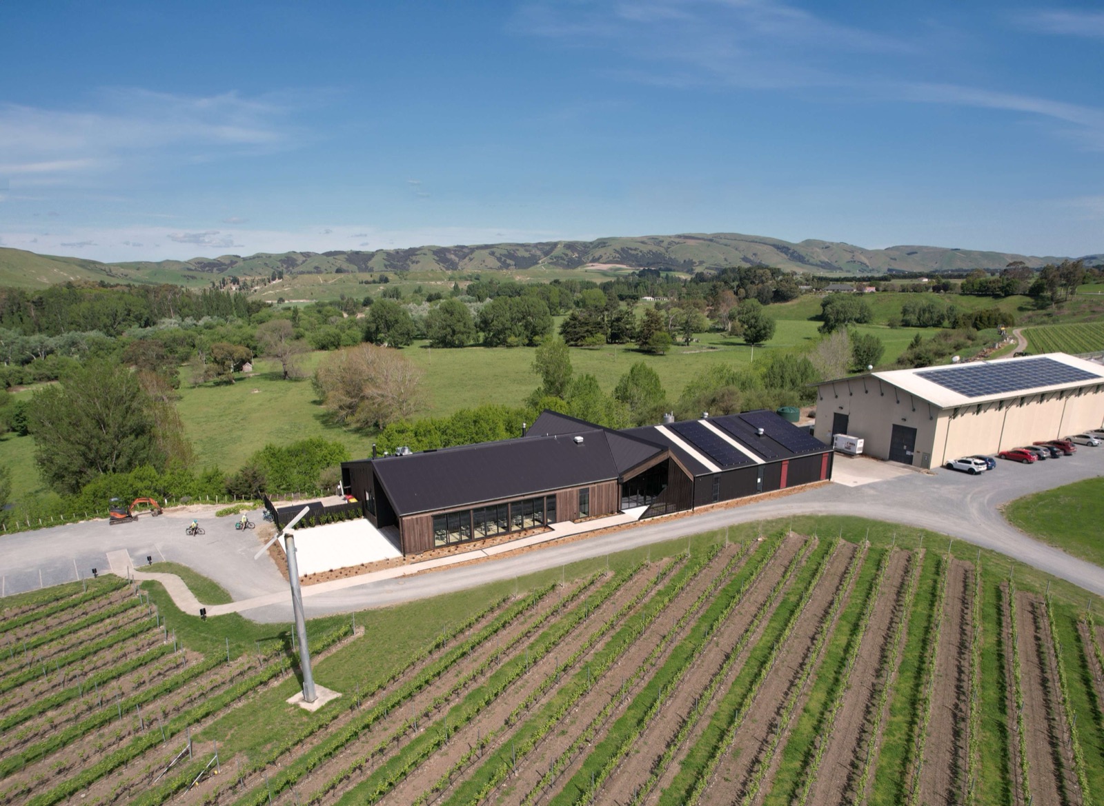 Aerial view of The Runholder at Te Kairanga Winery with a dark metal roof and solar panels among vineyards