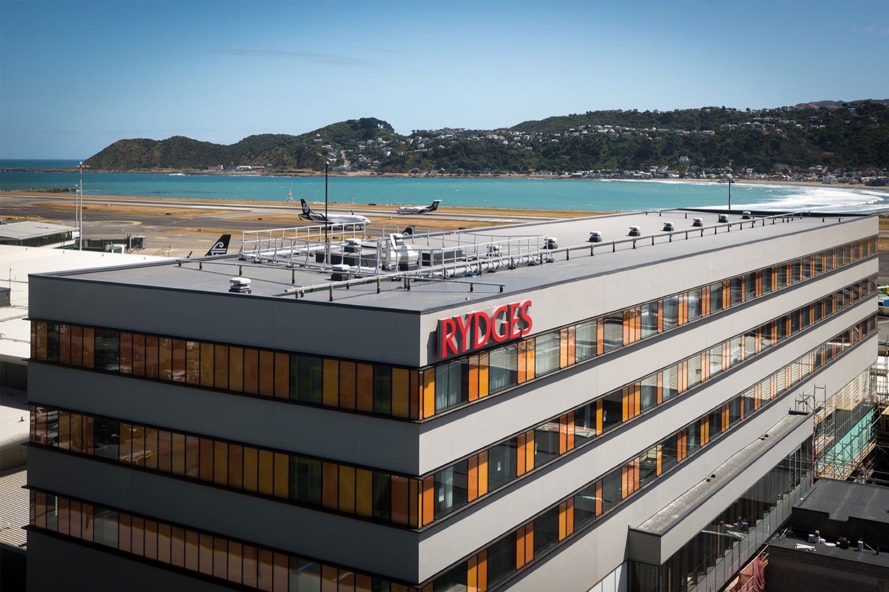 Rydges Wellington Airport hotel with flat membrane roof overlooking the coastline