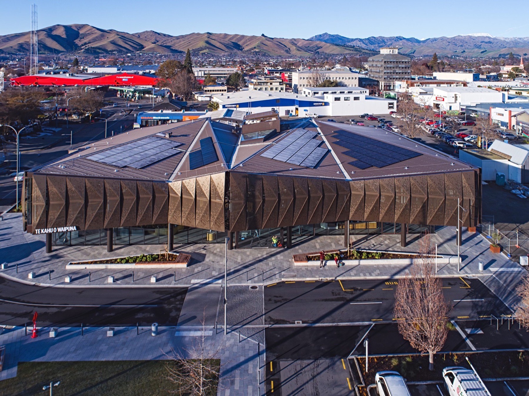 Aerial view of a civic building with a folded bronze facade and standing seam roof